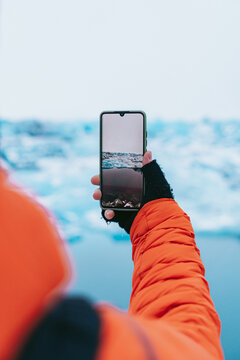 Man photographing a glacier with his smartphone.