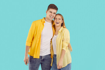 Portrait of smiling young couple isolated on blue studio background hug and laugh enjoy healthy relationships. Happy man and woman embrace show love and care. Relations concept.