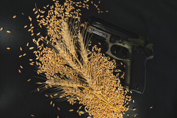 Gun on a black background and grains of wheat scattered around