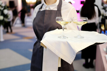 The waiter greets visitors of the event with glasses of champagne on a tray