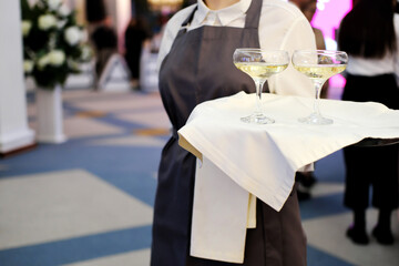 The waiter greets visitors of the event with glasses of champagne on a tray