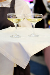 Waiter greets party guests with glasses of champagne on a tray