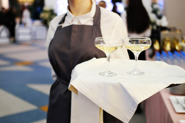 Waiter greets party guests with glasses of champagne on a tray