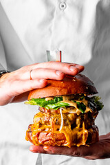 chef holding triple cheeseburger in hand