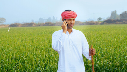 A confident modern farmer making a call while standing in his agricultural field - Indian Model ....