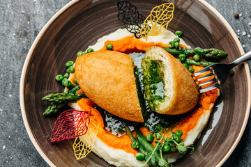 Chicken Kiev cutlet breast stuffed with butter, garlic and herbs served with asparagus and peas....