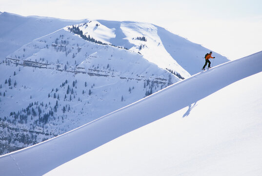 A backcountry skier climbs a snowy ridgeline while ski touring on a sunny day in the western Teton range, Wyoming.