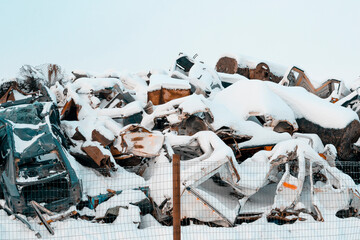 Junkyard with scrap metal and damaged cars during winter season