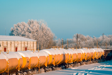 Snow covered tank-wagons with a crude oil standing on the railway