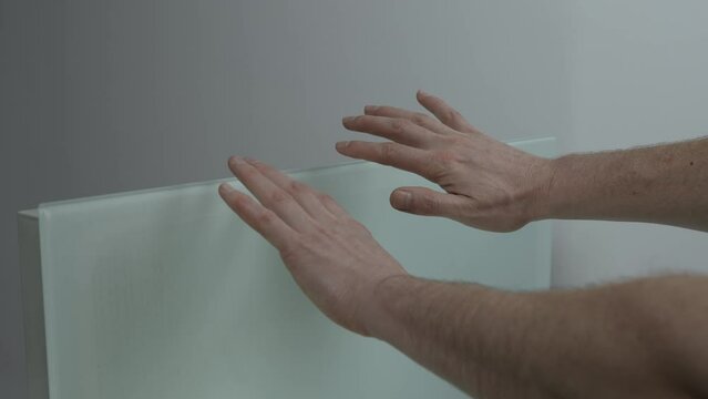 A man warms his hands over a wall-mounted electric heater. Additional heating system. Close-up. High quality 4k footage