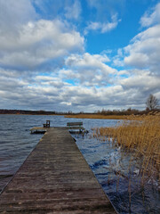 Fototapeta na wymiar wooden old dock on lake with beautiful clouds in the blue sky