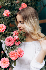 attractive model among floral roses in a white dress