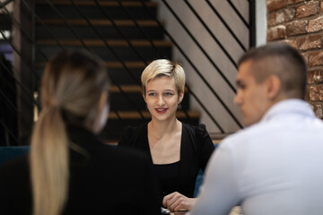 Three young business colleagues having a meeting in a modern cafe. Successful startup team brainstorming.