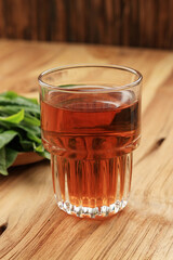 Warm Tea in A glass, with Fresh Tea Leaf Background