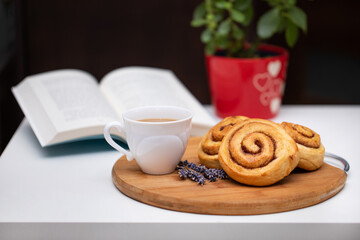 Obraz na płótnie Canvas Sweet cinnamon buns, coffee with milk and a book, traditional swedish kanelbullar buns