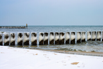 Empty wide beach in władysławowo in winter scenery. Wooden spurs covered with snow and ice. Poland, Baltic Sea during winter