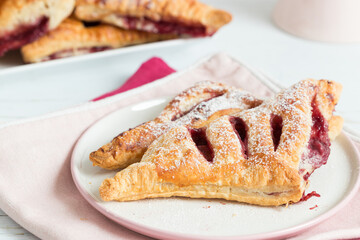 Berry jam filled puff pastry, served on pink and white background