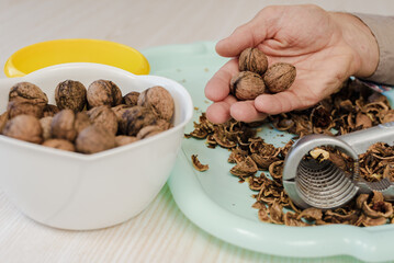 Process of peeling walnuts at home and nutcracker lying on table