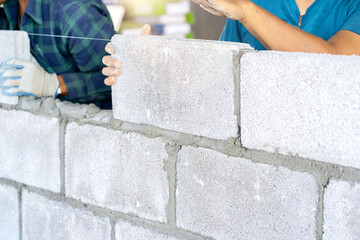 masonry worker make concrete wall by cement block and plaster at construction site