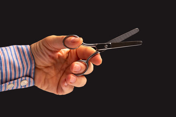 hand holds scissors on a dark background. tailor and barber profession