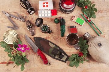 Items for survival in nature on a wooden table on a camouflage karemat.