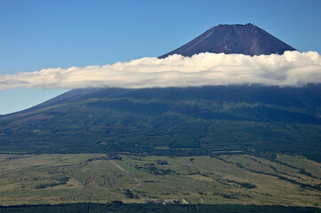 道志山塊の杓子山山頂より望む夏の富士山
杓子山は道志山塊の西に聳える山。富士吉田市と都留市、そして忍野村との行政界に位置する山。遠方から杓子山方面を眺めると富士山に近いこともありすぐにそれと分かるが、そのときに最も標高が高い山容は鹿留山或いは子ノ神であり、その隣のやや低い場所の山が杓子山になる。山梨百名山である杓子山の山頂からは、天候に恵まれれば四囲に視界を遮る樹木はほとんどないことから360度の