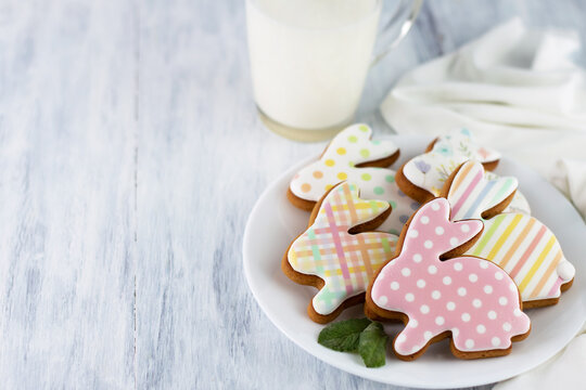 Blurred image of multicolored, easter bunny-shaped cookies on a gray table.