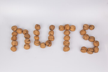 Nuts - an inscription made of walnuts isolated on a white background. Top view, flat lay.
