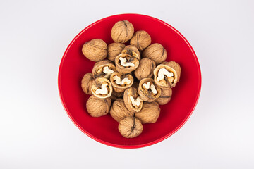 Walnuts in a red bowl isolated on white background. Nuclei in the shape of a heart. Healthy breakfast concept. Valentine's Day.