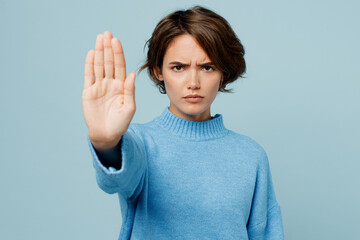 Young strict serious sad caucasian woman wear knitted sweater look camera showing stop gesture with...