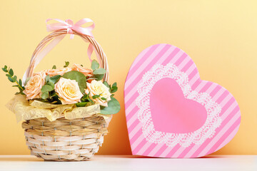 Valentine's day, mother's day, birthday. Flowers in a basket and a pink box with a heart-shaped gift on the table. still life