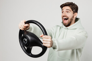 Side view young happy fun shocked surprised caucasian man in mint hoody look camera hold steering...