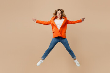 Fototapeta na wymiar Full body young employee business woman corporate lawyer wear classic formal orange suit glasses work in office jump high with outstretched hands look camera isolated on plain beige background studio.