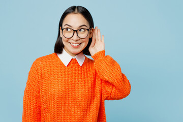 Young curious nosy woman of Asian ethnicity wear orange sweater glasses try to hear you overhear...