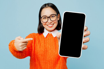 Young woman of Asian ethnicity wearing orange sweater glasses hold in hand use point finger on...