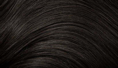Brunette or black hair. Female long dark hair in black. Beautifully laid curls. Closeup texture in a dark key. Hairdressing, hair care and coloring. Shading gray hair. Background with copy space.