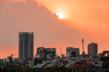 HOCHIMINH CITY, VIETNAM - JANUARY 19, 2022: beautiful sunset sky with rare orange-pink color, the sun is round like egg yolk, foreground is Saigon river and old houses