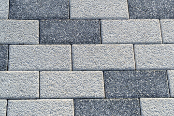 Obraz premium Covering the footpath of light and dark gray tiles. Modern textured paving tiles of rectangular shape. Traditional backyard or road paving
