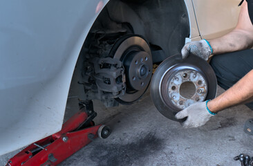 Replacing brake discs on a car. Removed the old brake disc from the car and installed the new brake disc. Car maintenance - obrazy, fototapety, plakaty