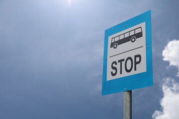 Bus stop sign in the street against blue sky