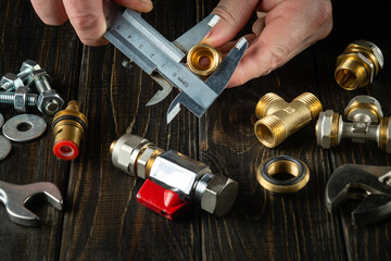 Master plumber measures the diameter of a fitting with a caliper. Working environment in the workshop when connecting gas equipment