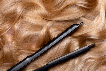 Iron for straightening and styling hair in a beauty salon. Curling your hair into beautiful wavy curls with a hair straightener. Flat lay top view as background with place for text.