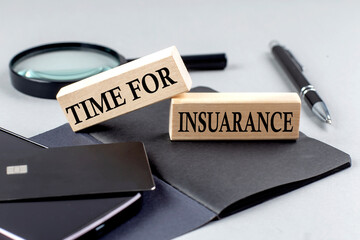 TIME FOR INSURANCE text on wooden block on black notebook , business concept