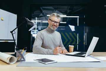 Portrait of senior architect, gray haired designer smiling and looking at camera, man mock up plan...