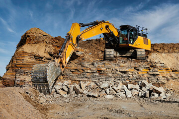 Yellow Excavator breaking rocks in a quarry