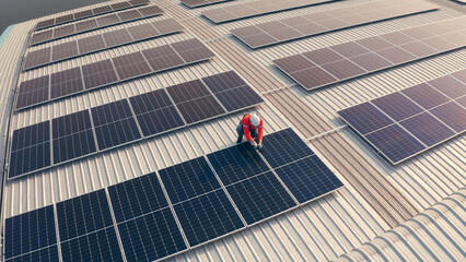 Drone shot, Male engineer maintaining solar cell panels on rooftop. Technician working outdoor on...