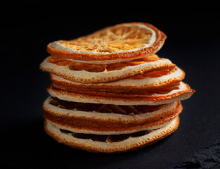 a stack of dried round orange slices on a black background