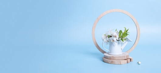 Banner with spring still life composition with miniature watering can and blossom twigs. Copy space on blue background