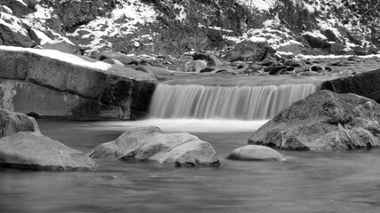 Small waterfall from a stream in winter in black and white