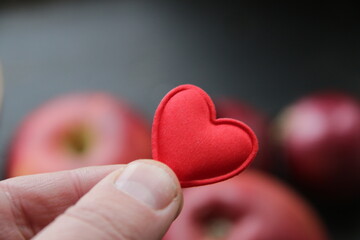 Healthy food concept. Hand holding a heart on the background of an apple.